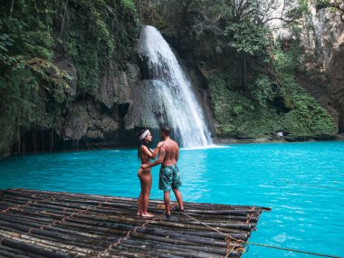 Cebu Adası Kawasan Şelalesi turkuaz su ile şelale önünde bambu sal üzerinde yalnız seyahat çift, Filipinler