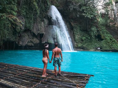 Cebu Adası Kawasan Şelalesi turkuaz su ile şelale önünde bambu sal üzerinde yalnız seyahat çift, Filipinler