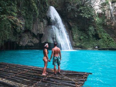 Cebu Adası Kawasan Şelalesi turkuaz su ile şelale önünde bambu sal üzerinde yalnız seyahat çift, Filipinler