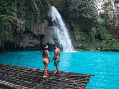 Cebu Adası Kawasan Şelalesi turkuaz su ile şelale önünde bambu sal üzerinde yalnız seyahat çift, Filipinler