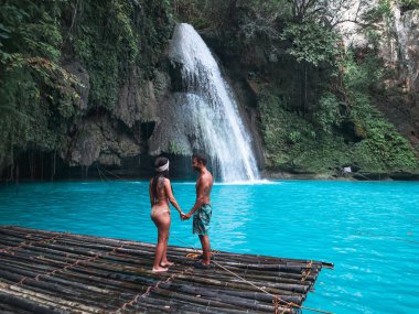 Cebu Adası Kawasan Şelalesi turkuaz su ile şelale önünde bambu sal üzerinde yalnız seyahat çift, Filipinler