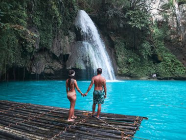 Cebu Adası Kawasan Şelalesi turkuaz su ile şelale önünde bambu sal üzerinde yalnız seyahat çift, Filipinler