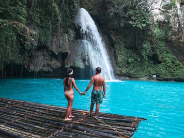 Cebu Adası Kawasan Şelalesi turkuaz su ile şelale önünde bambu sal üzerinde yalnız seyahat çift, Filipinler