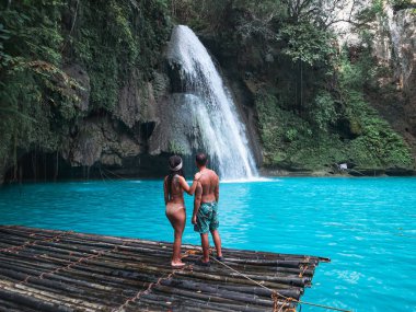 Cebu Adası Kawasan Şelalesi turkuaz su ile şelale önünde bambu sal üzerinde yalnız seyahat çift, Filipinler