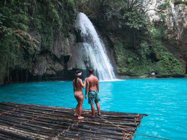 Cebu Adası Kawasan Şelalesi turkuaz su ile şelale önünde bambu sal üzerinde yalnız seyahat çift, Filipinler