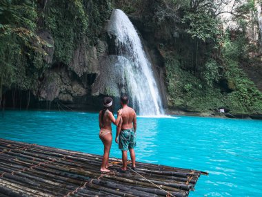 Cebu Adası Kawasan Şelalesi turkuaz su ile şelale önünde bambu sal üzerinde yalnız seyahat çift, Filipinler