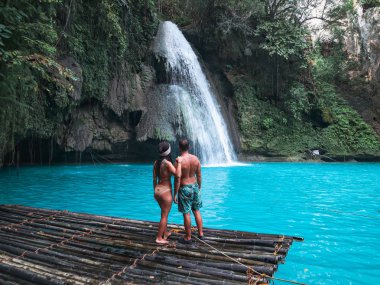 Cebu Adası Kawasan Şelalesi turkuaz su ile şelale önünde bambu sal üzerinde yalnız seyahat çift, Filipinler