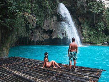 Cebu Adası Kawasan Şelalesi turkuaz su ile şelale önünde bambu sal üzerinde yalnız seyahat çift, Filipinler
