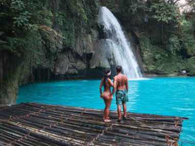 Cebu Adası Kawasan Şelalesi turkuaz su ile şelale önünde bambu sal üzerinde yalnız seyahat çift, Filipinler