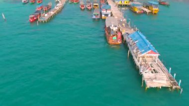 Kamboçya Koh Rong iskele ve Uzun Kuyruk Tekneler ile palmiye ağaçları ile çevrili Koh Touch köy kıyısı hava manzara. Tropik adada turistik yerler. Egzotik tatil beldesi