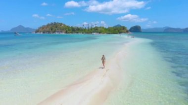 Yılan Adası 'nın havadan kara sapı, Sandbar' daki kadın ve turkuaz suyla gölün üzerinden uç. El Nido, Palawan. Filipinler.
