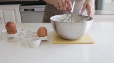Lezzetli peynirli kek kulübesinde yumurta karıştıran kadın. Metal tencerede adım adım yanmış cheesecake hazırlama