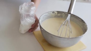 Lezzetli peynirli keki karıştıran ve metal tencerede yanmış peynirli keki hazırlayan kadın. Lezzetli Bask peynirli kek yapıyorum. Metal tencerede adım adım San Sebastian peynirli kekinin hazırlanması
