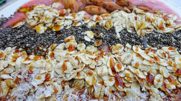 用椰子片 奇亚种子 杏仁和格拉诺拉装饰在粉红背景下的冰沙碗 早餐碗 有水果和麦片 健康的素食 — 图库照片