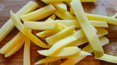 Çiğ patates dilimlenmiş şeritler tahtadan arkaplanlı patates kızartması için hazırlandı.