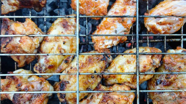 Chicken wings on barbecue grill with fire close up. Chicken meat on the grill