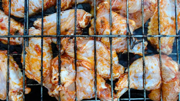 Chicken wings on barbecue grill with fire close up. Chicken meat on the grill