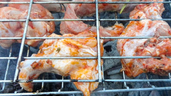 Chicken wings on barbecue grill with fire close up. Chicken meat on the grill