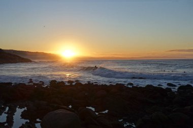 Dalgada sörfçü, gün doğumu, güney Afrika