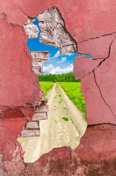 Ancient cement and brick wall with cracks on rural landscape background.