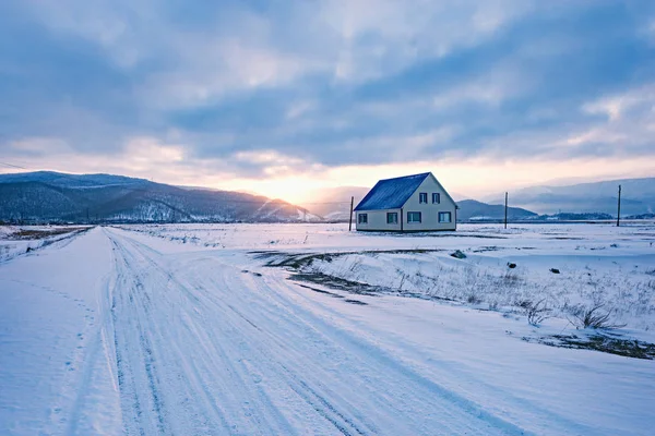 Small road to the settlement at cold winter sunset time.