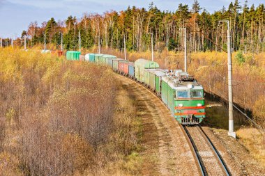 Uzun yük treni sonbahar günü istasyona yaklaşır..