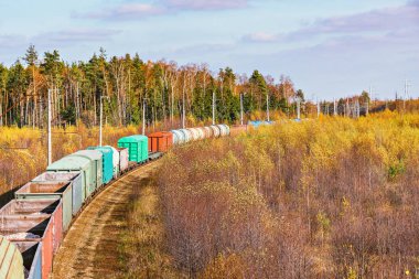 Uzun yük treni sonbahar günü istasyona yaklaşır..