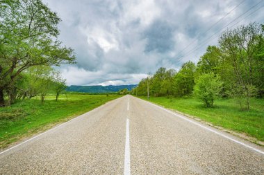Asfalt yol dramatik fırtınalı gökyüzü altında dağlara