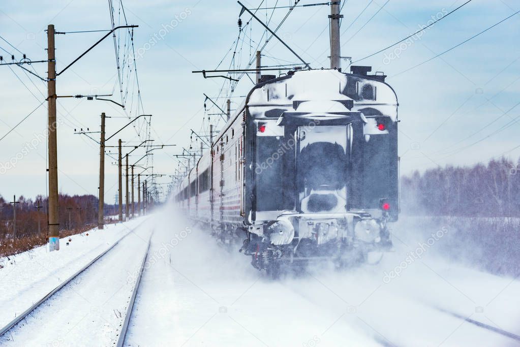 Passenger train moves at winter day time.