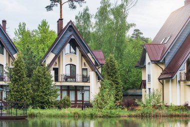 Yağmurlu bahar gündüz orman göl kenarında özel lüks evler.