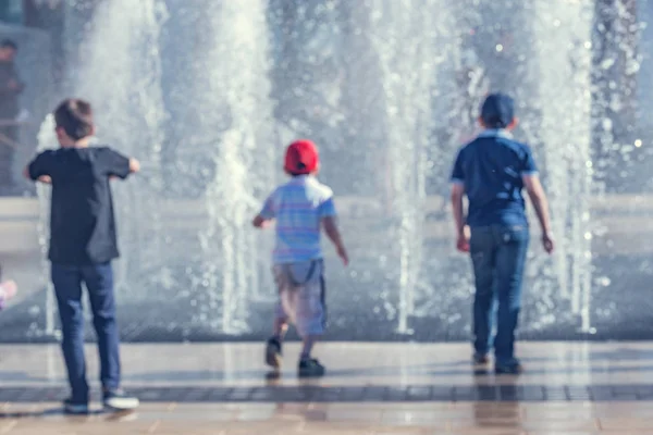 Niños divirtiéndose junto a la fuente en un día soleado . —  Fotos de Stock