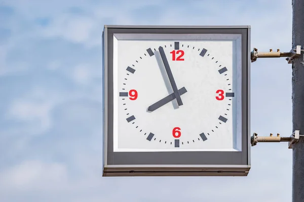 Railway station clock on the column on sky background.