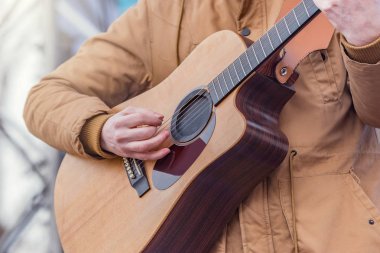 Sahnede akustik gitar çalan adamın elleri.