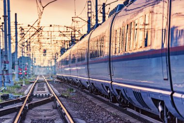 Yolcu treni gün batımında istasyondan ayrılıyor..