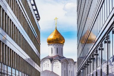 İki modern bina arasında Ortodoks kilise kulesi.