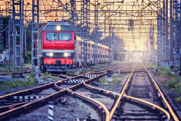 Yolcu treni gün batımında istasyondan ayrılıyor.. — Stok fotoğraf