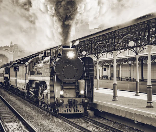 Retro trein vertrekt vanaf het stationsgebouw. — Stockfoto