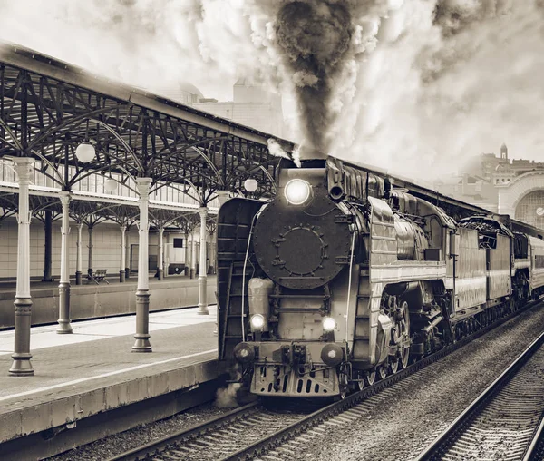 Retro trein vertrekt vanaf het stationsgebouw. — Stockfoto