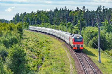 Yolcu treni yaz sabahı istasyona yaklaşıyor.