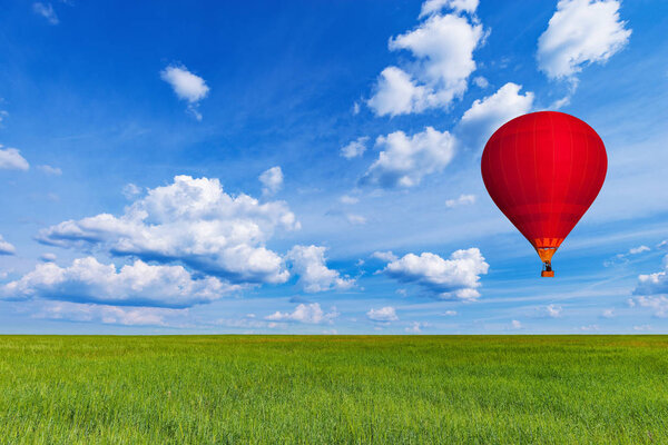 Red hot air balloon above the field with rye at day time.