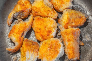 Sıcak tavada kızarmış balık parçaları.