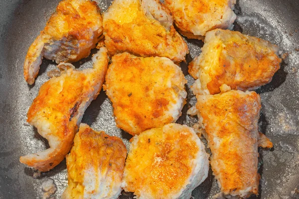 Sıcak tavada kızarmış balık parçaları.