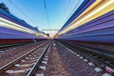 İki tren gün batımında farklı yönlere hızlı hareket.