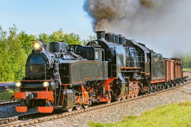 Buharlı yük treni tren istasyonundan yola çıkıyor.