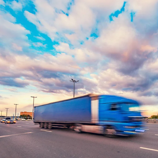 Camión de carga se mueve rápido en la carretera al atardecer . — Foto de Stock