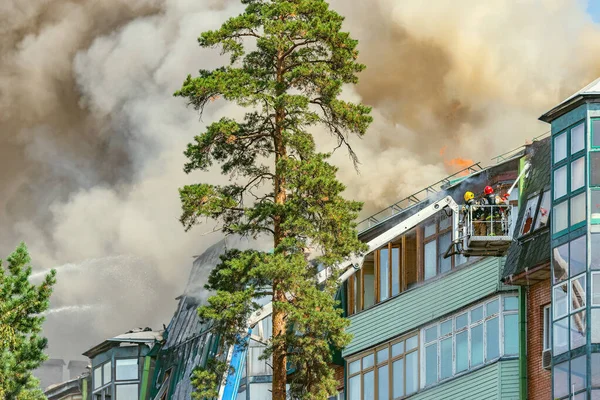 Bombeiros extinguem um incêndio no topo do prédio . — Fotografia de Stock