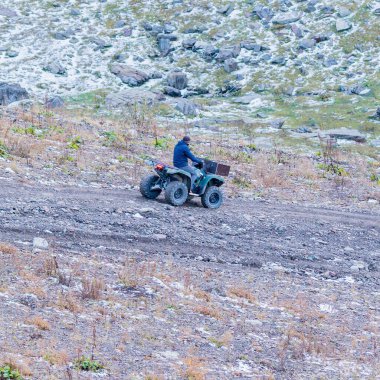 Adam Atv Quad Bisiklet dağlar yolda.