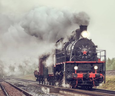 Şiddetli yağmurun altında geriye doğru buharlı yük treni.