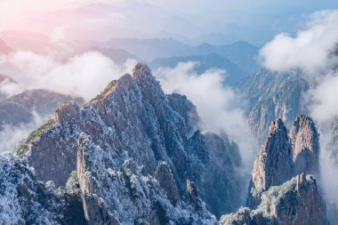 Huangshan Ulusal Parkı 'nın dağlık tepelerinde güneş doğarken bulutlar. Çin.