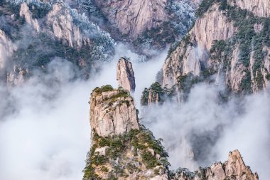 Huangshan Ulusal Parkı 'nın dağlık tepelerinde güneş doğarken bulutlar. Çin.